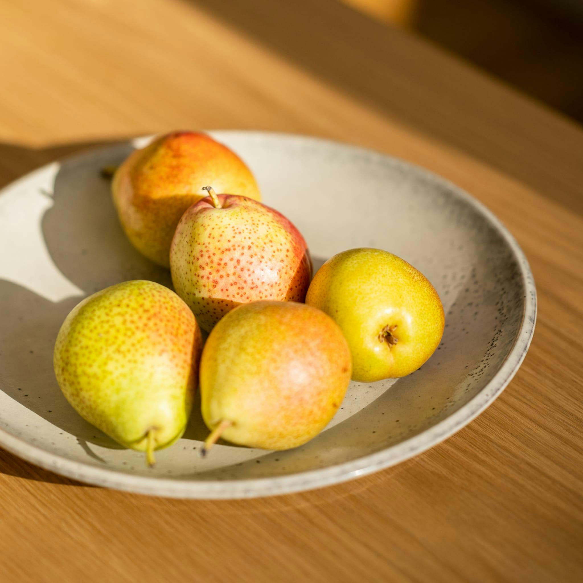 Pears on a white plate on a wooden table.